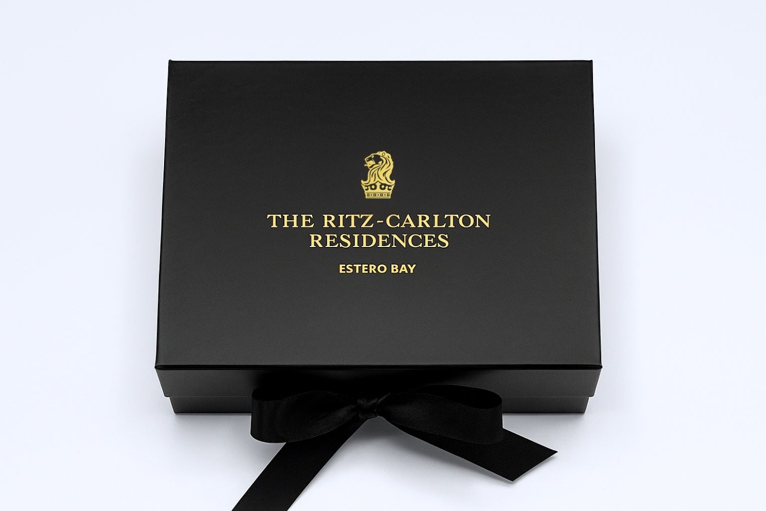 Gold foil logo on a black ribbon-tie gift box